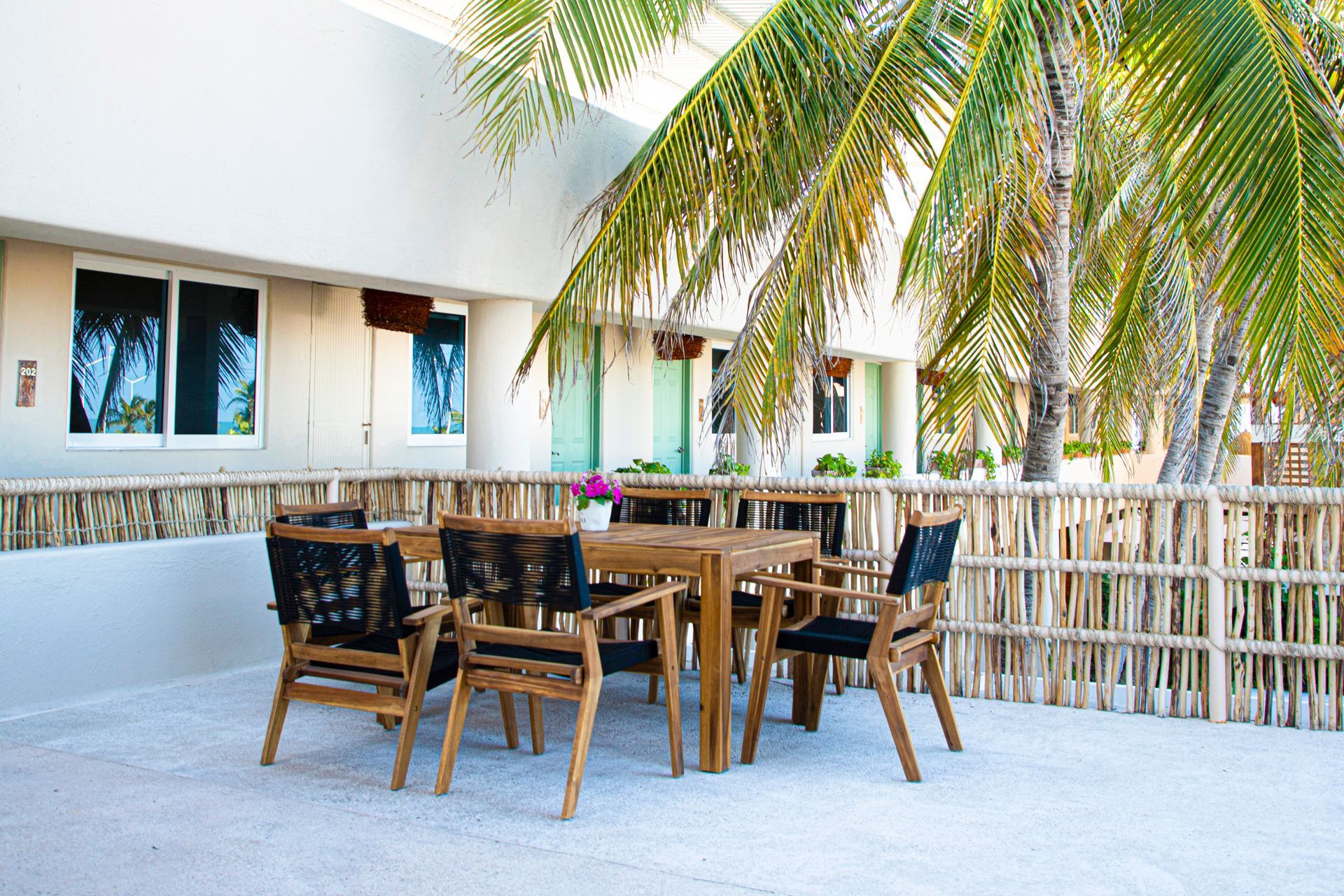 Un patio con mesa y sillas bajo palmeras.