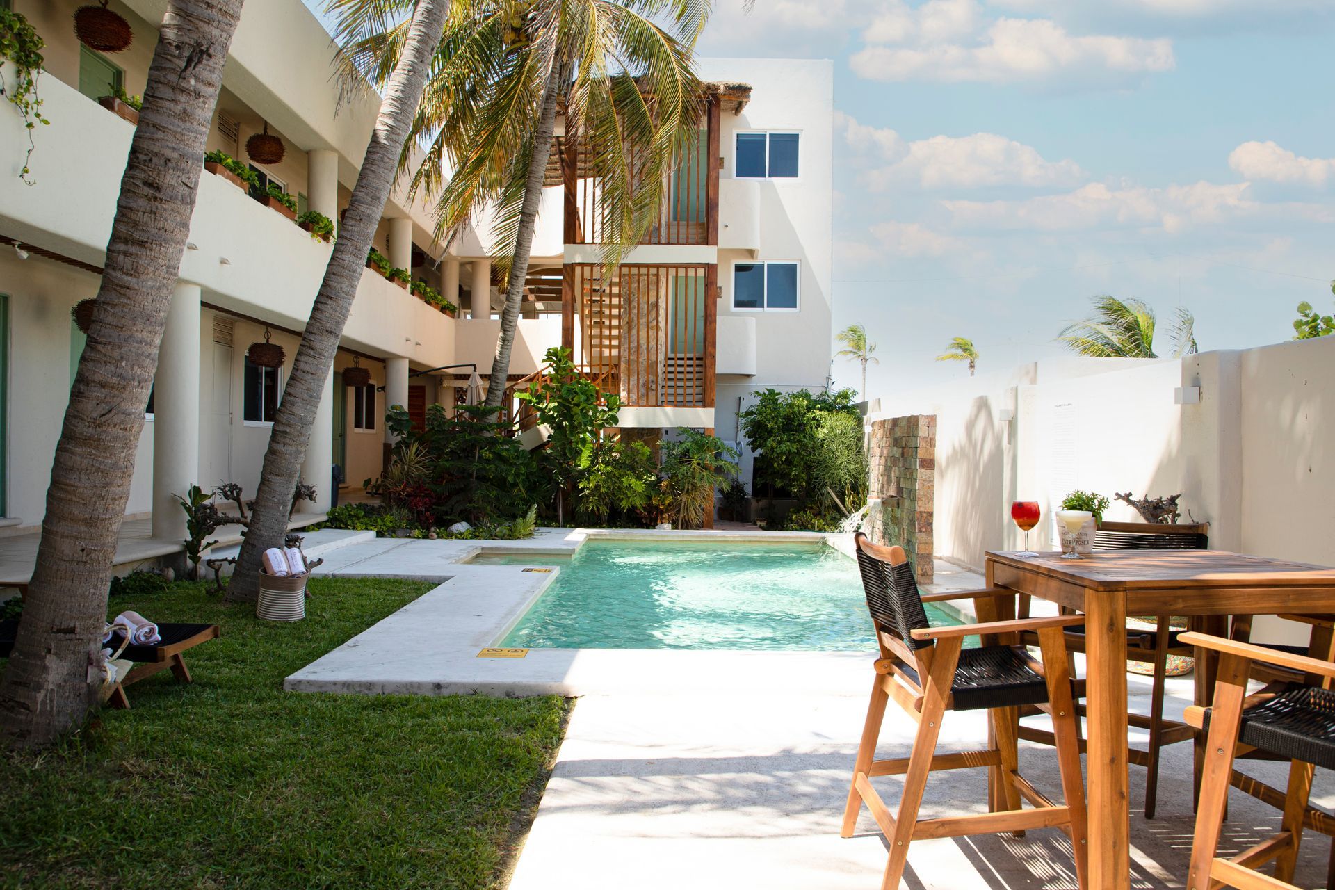 Una piscina con una mesa y sillas frente a un edificio.