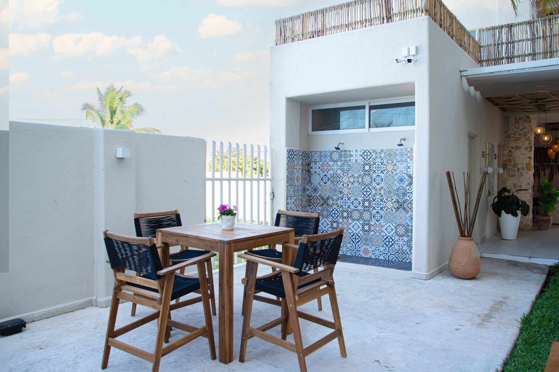 Un patio con una mesa y sillas frente a un edificio blanco.