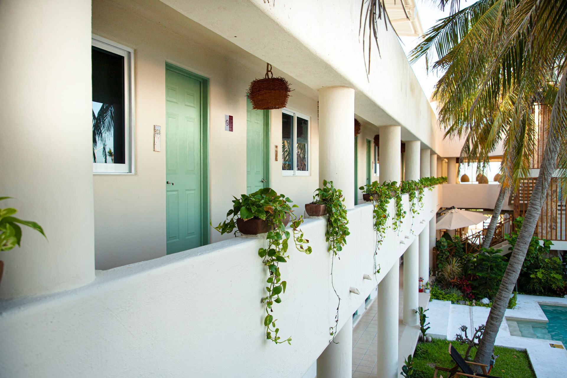 Un edificio blanco con una puerta verde y una piscina al fondo.