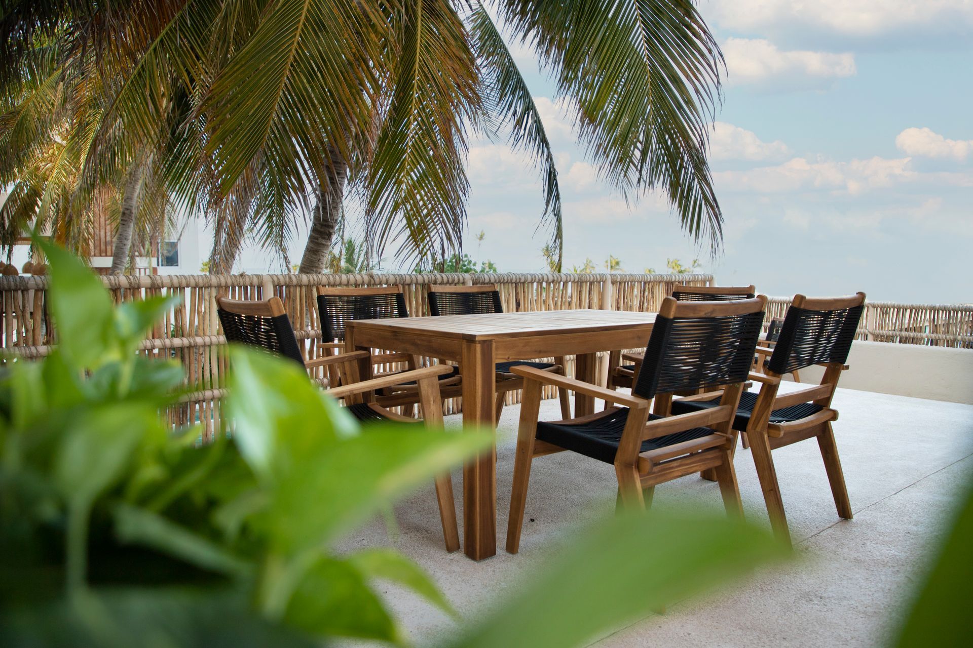 Una mesa y sillas están sentadas en la playa debajo de una palmera.