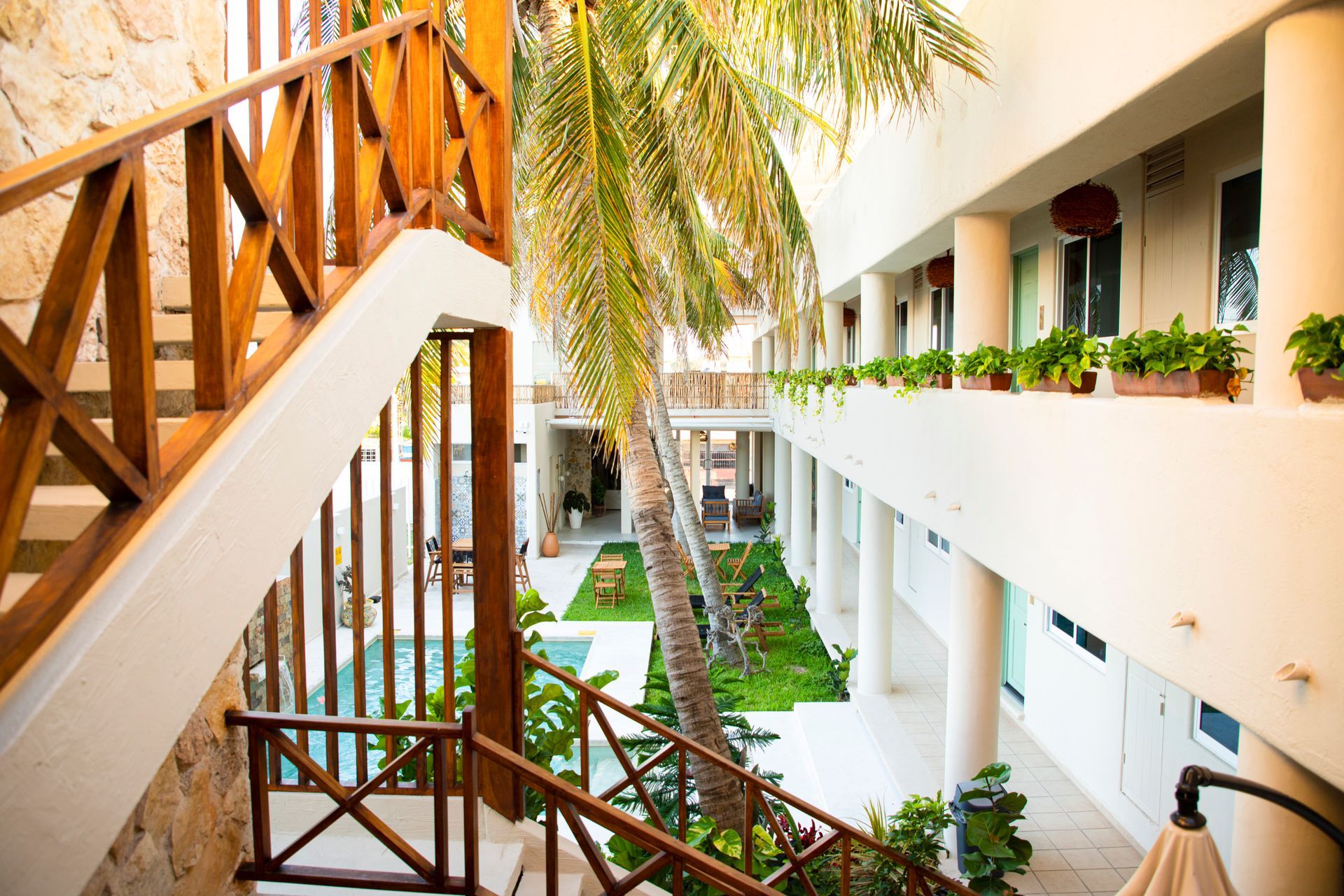 Un vestíbulo de hotel con escaleras que conducen a una piscina y palmeras.