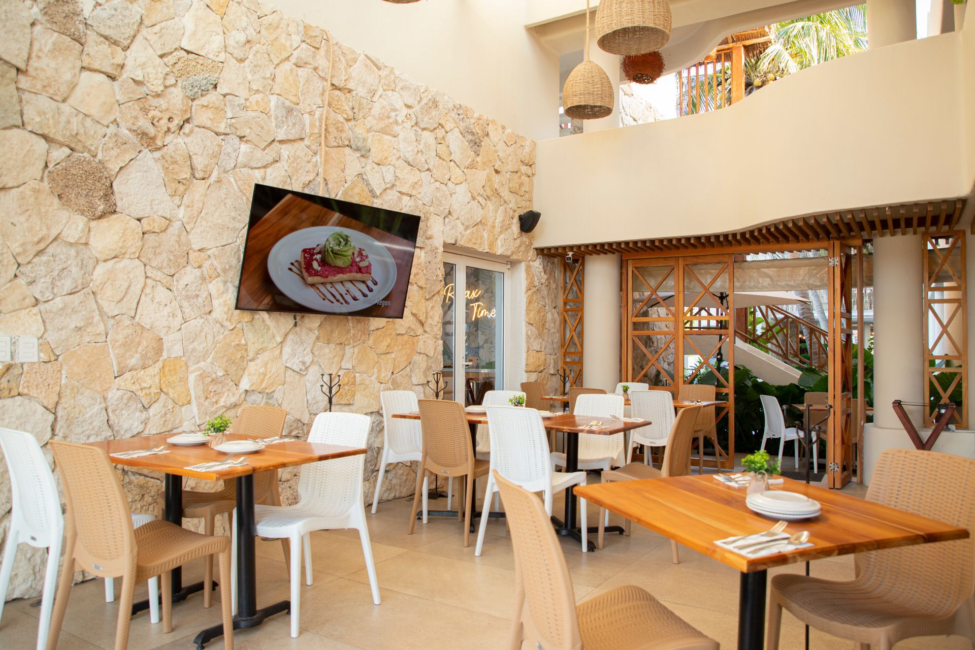 Un restaurante con mesas y sillas y un televisor en la pared.
