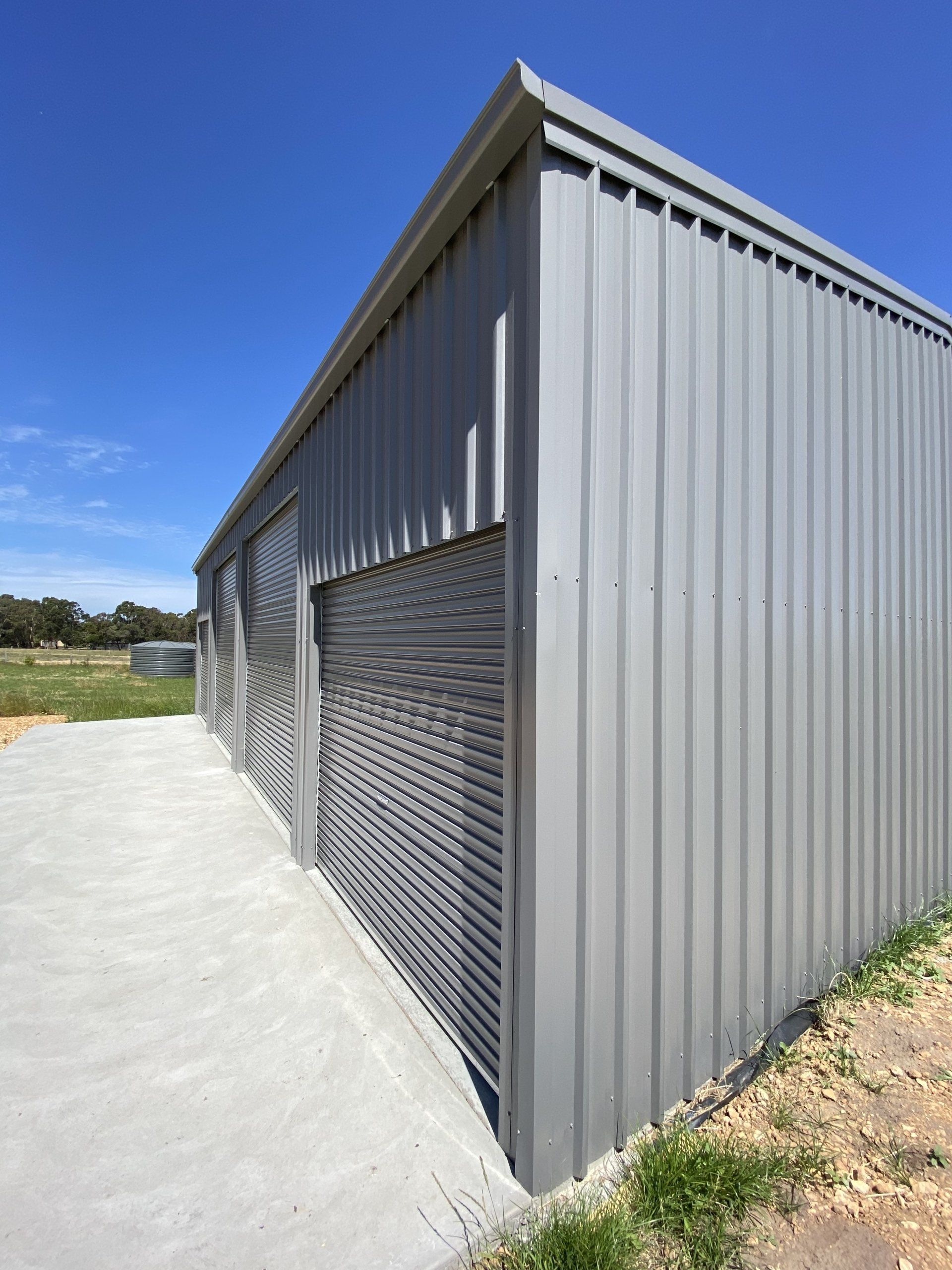 Gray metal building with concrete path, against blue sky.