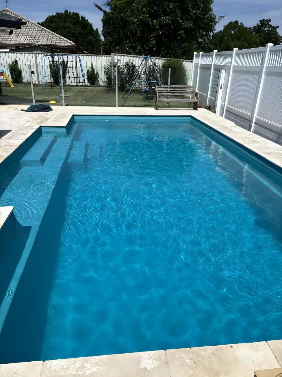 A Large Swimming Pool With A White Fence Surrounding It — Aqua Duck Pool Care In Landsborough, QLD