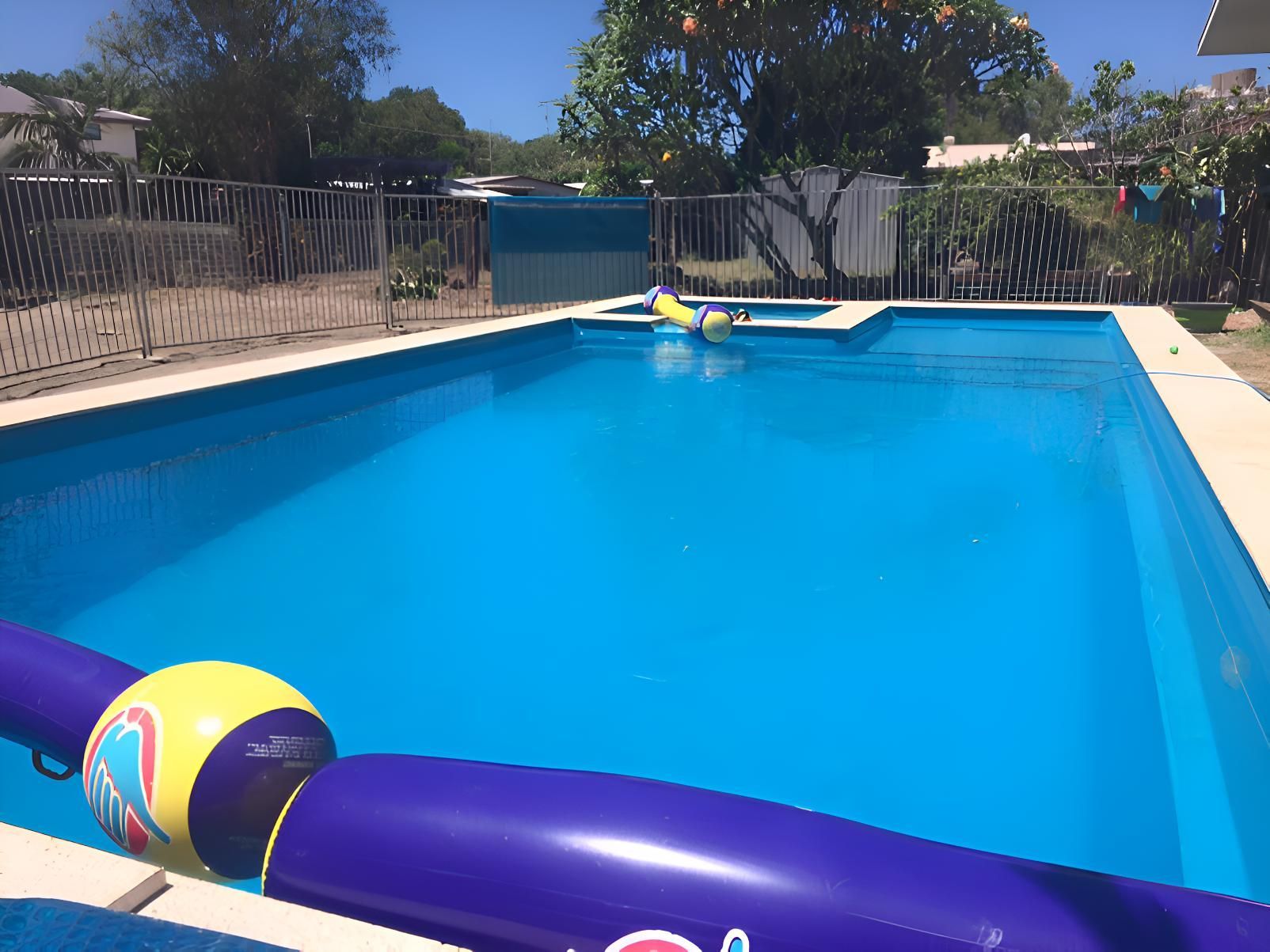 A Large Swimming Pool With A Purple And Yellow Ball In It — Aqua Duck Pool Care In Landsborough, QLD
