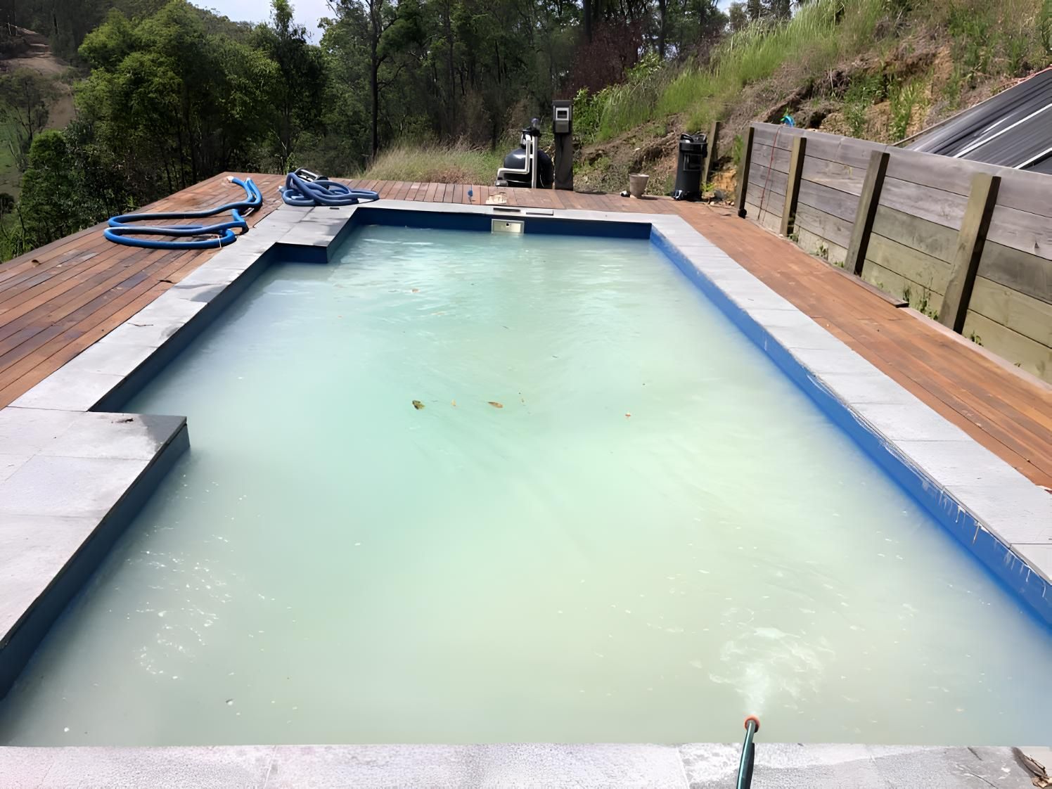 A Large Swimming Pool With A Blue Border And A Wooden Deck — Aqua Duck Pool Care In Landsborough, QLD