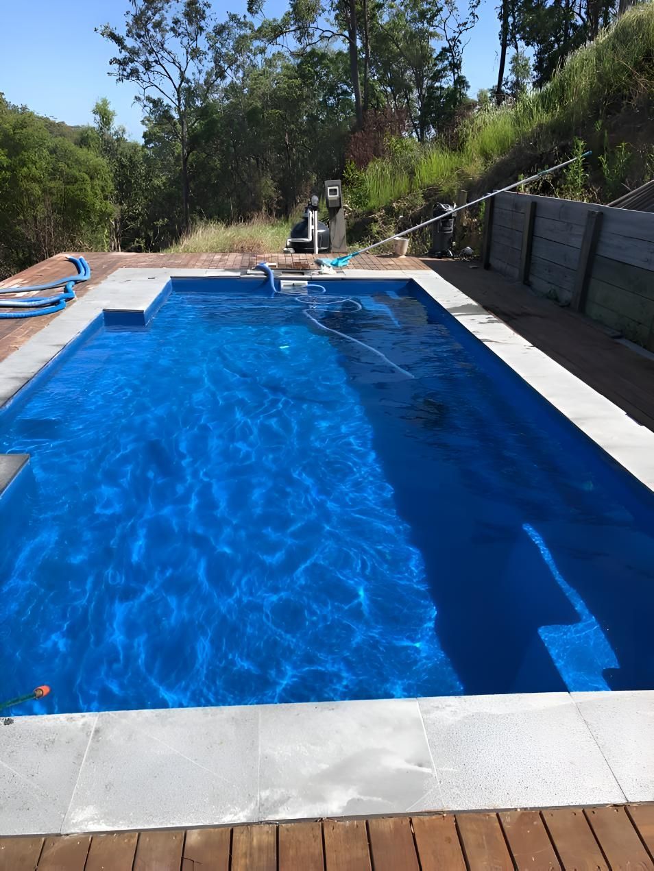 A Large Blue Swimming Pool With Trees In The Background — Aqua Duck Pool Care In Landsborough, QLD