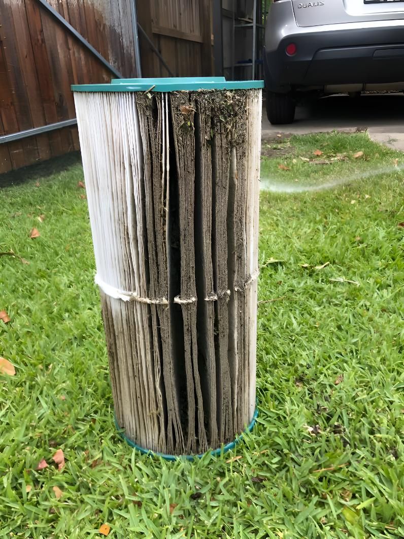 A Dirty Pool Filter Is Sitting In The Grass Next To A Car — Aqua Duck Pool Care In Landsborough, QLD