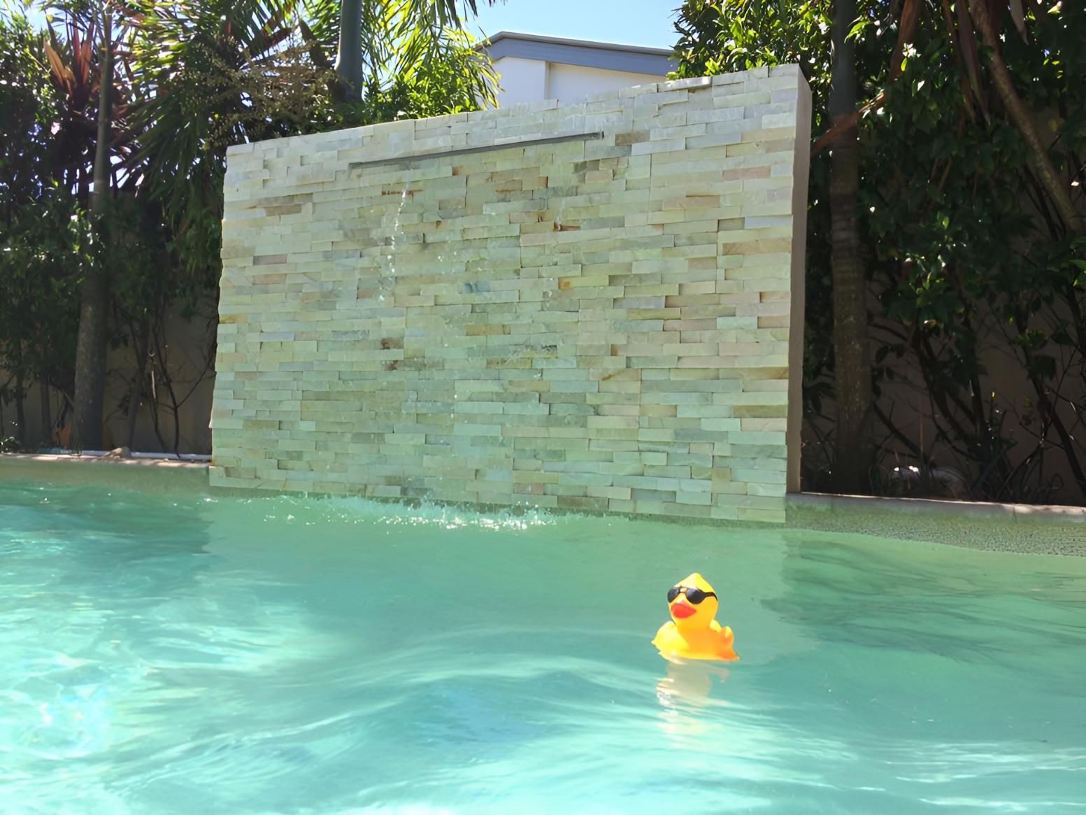 A Yellow Rubber Duck Wearing Sunglasses Is Floating In A Swimming Pool — Aqua Duck Pool Care In Landsborough, QLD