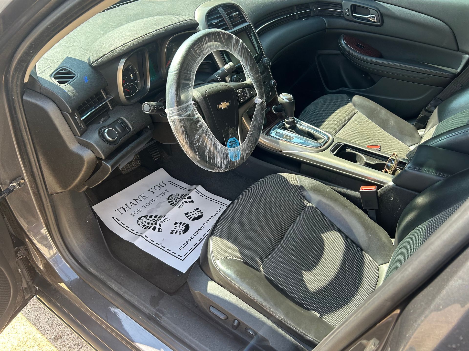 Interior of a car with a driver's seat, steering wheel, and center console. Dark gray and black details.