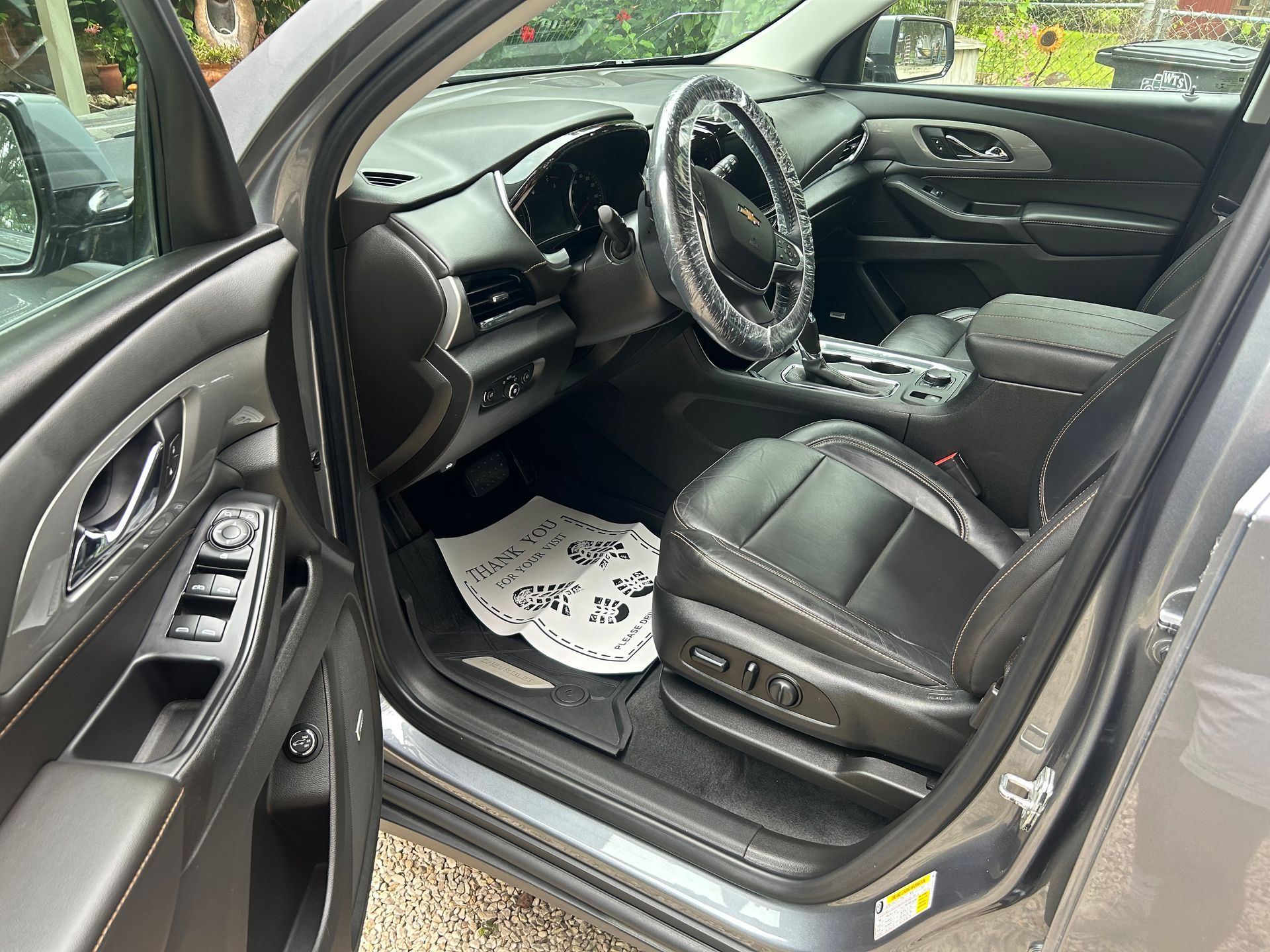 Gray car interior with driver's side door open, showing black leather seats, steering wheel, and dashboard.