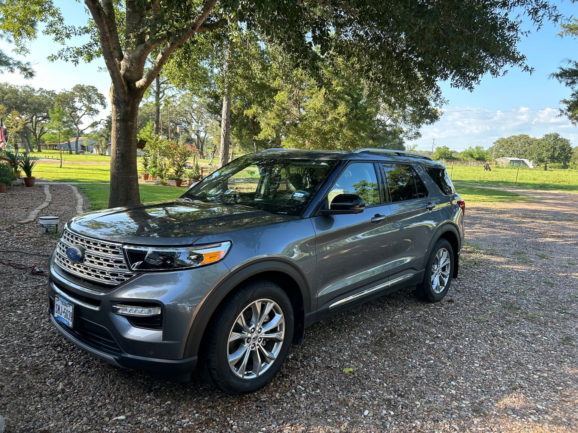 Gray Ford Explorer SUV parked on gravel under a tree, outdoors.