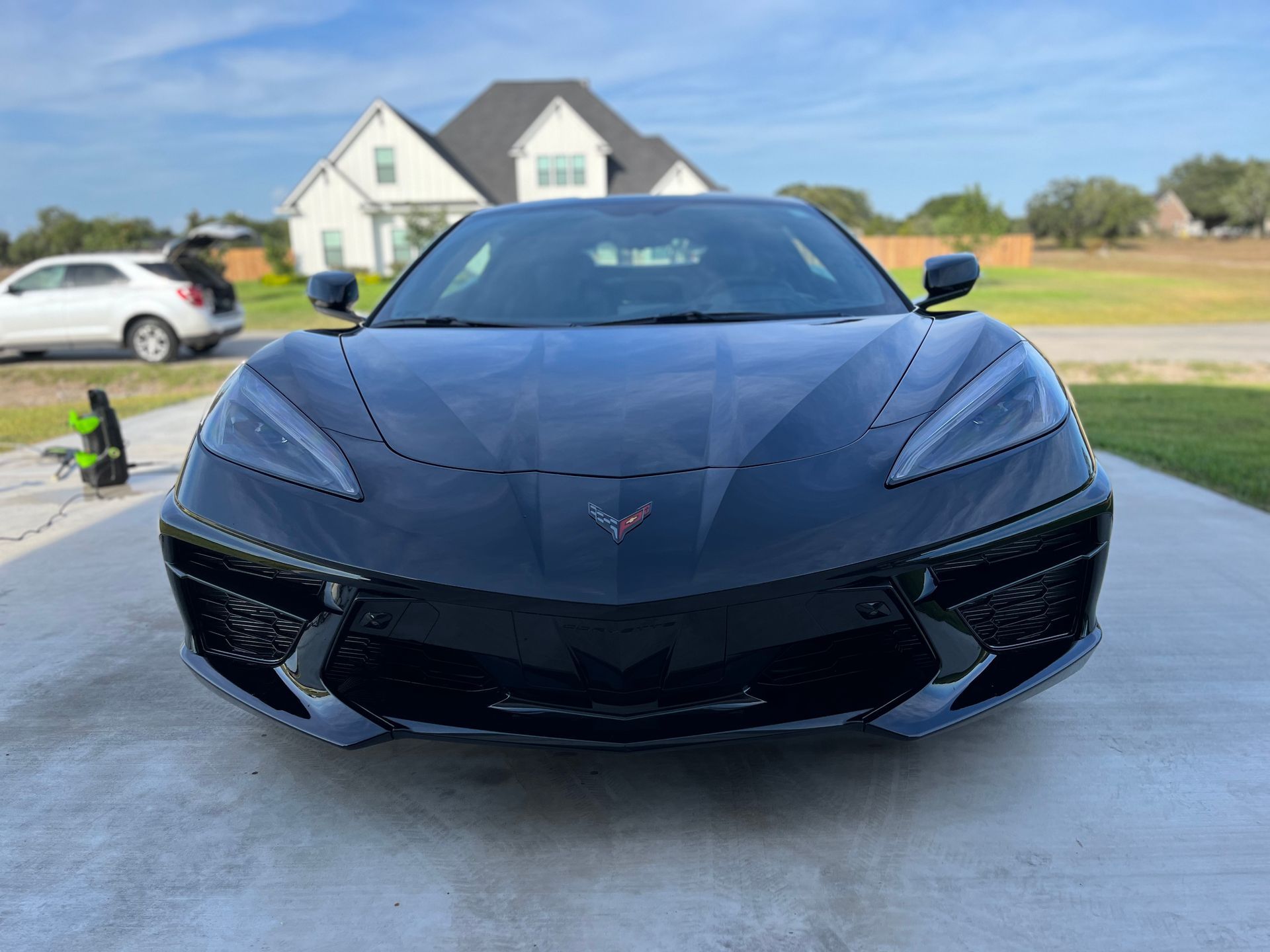Black Chevrolet Corvette parked on a driveway in front of a house.