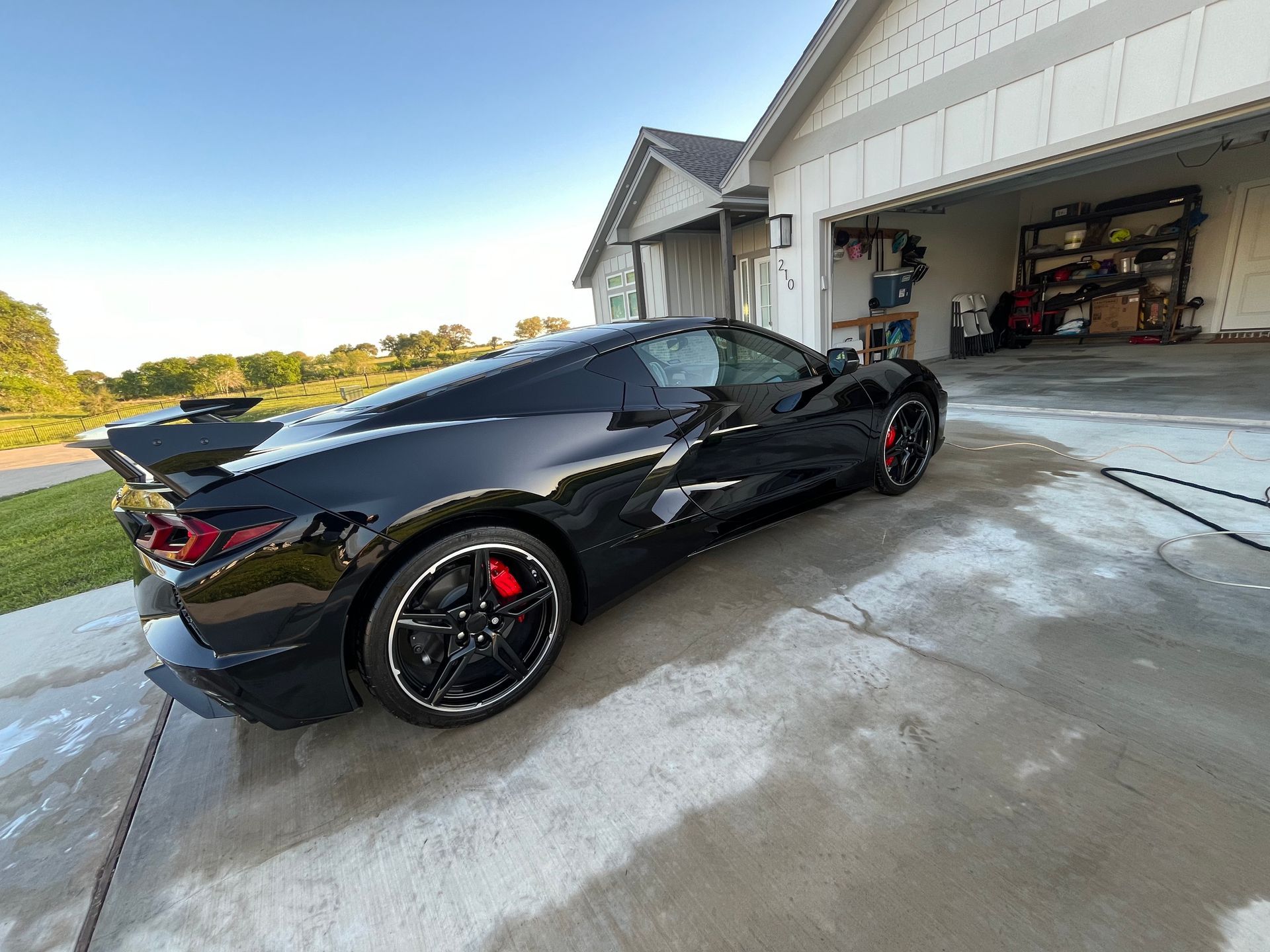 Black sports car parked on a driveway near a garage, washing the car.