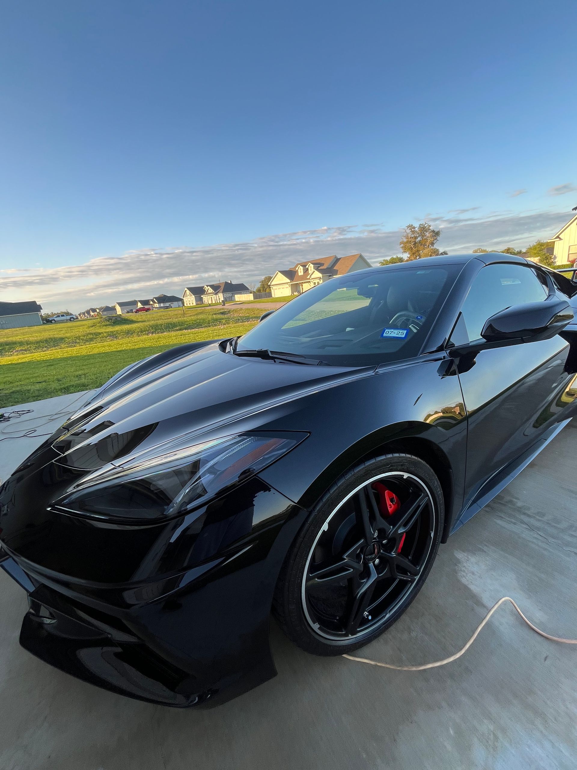 Black Chevrolet Corvette sports car parked on a driveway. Red brake calipers visible.