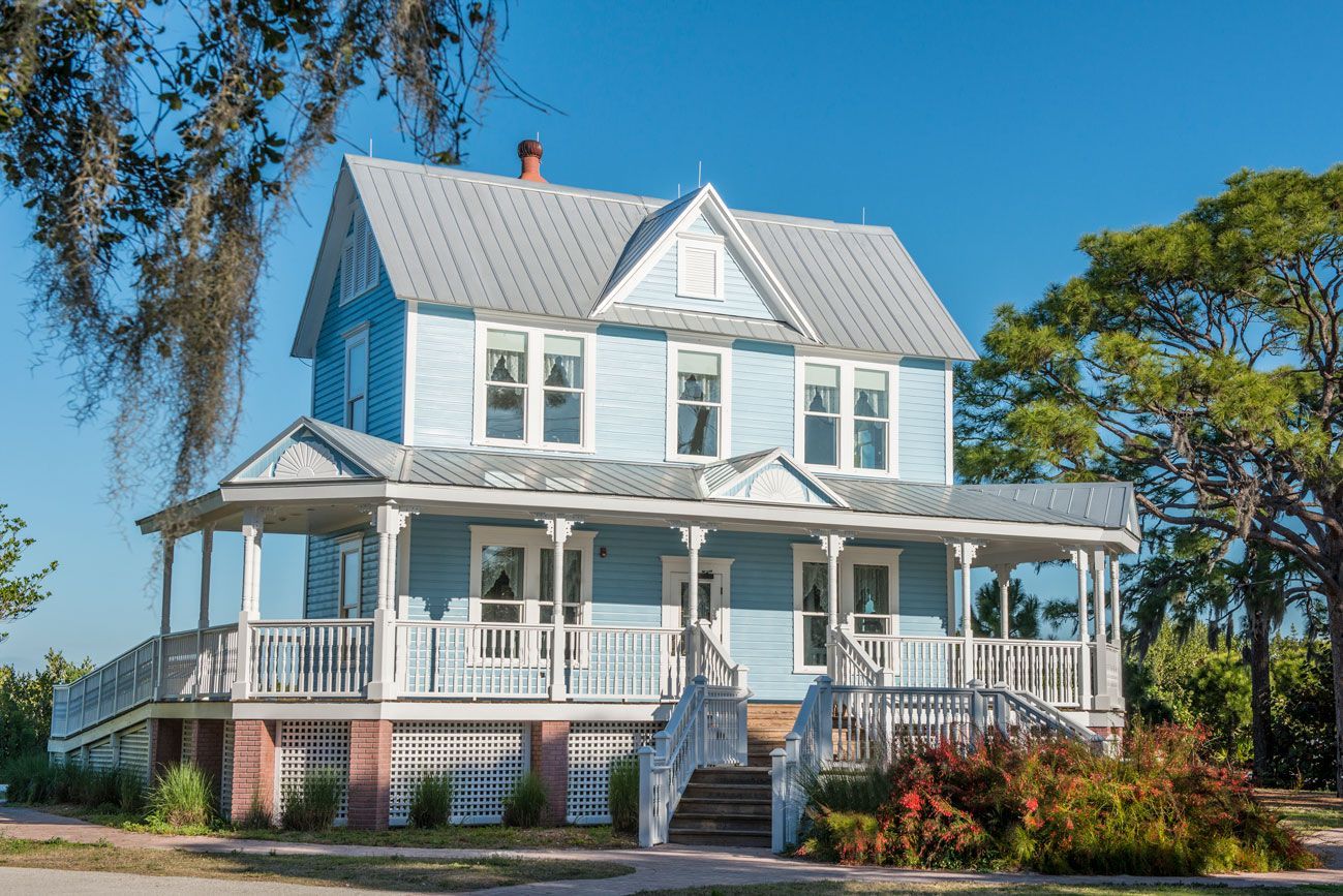 A large blue house with a large porch and stairs.