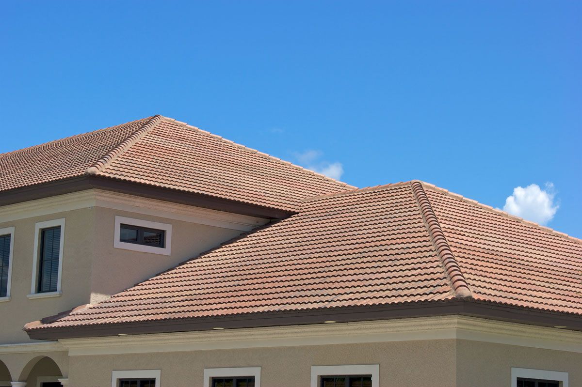 A large house with a tiled roof and a blue sky in the background.