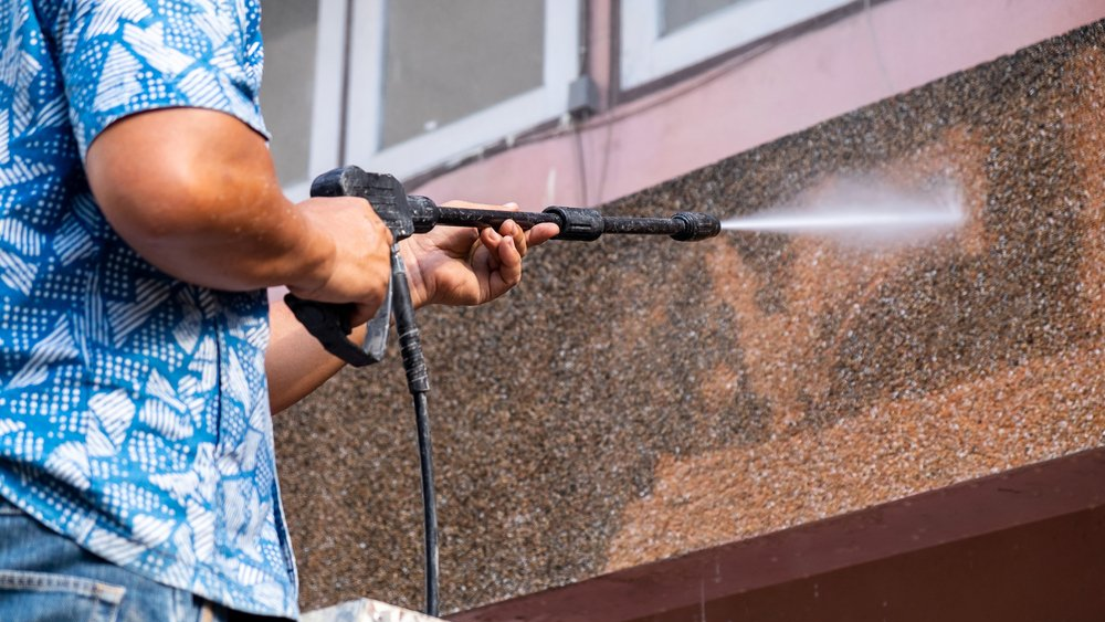 man pressure washing a building