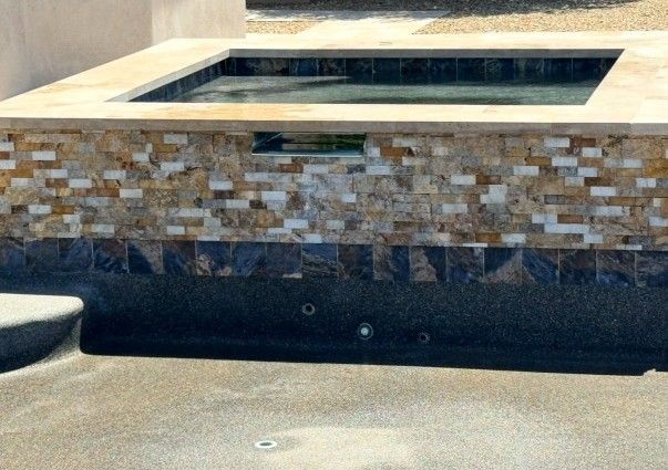 Hot tub with stone tile surround and waterfall feature; exterior.