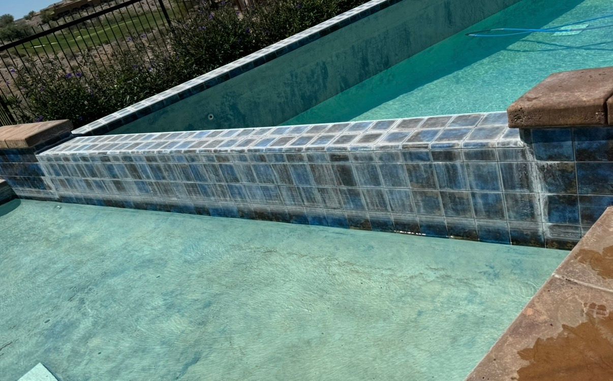 A rectangular pool with a cascading waterfall feature; blue-tiled wall, water flows over.