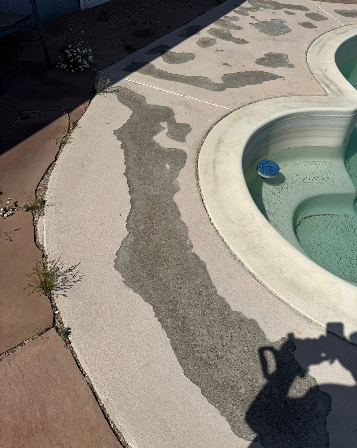 Wet concrete path next to a pool with a visible shadow.