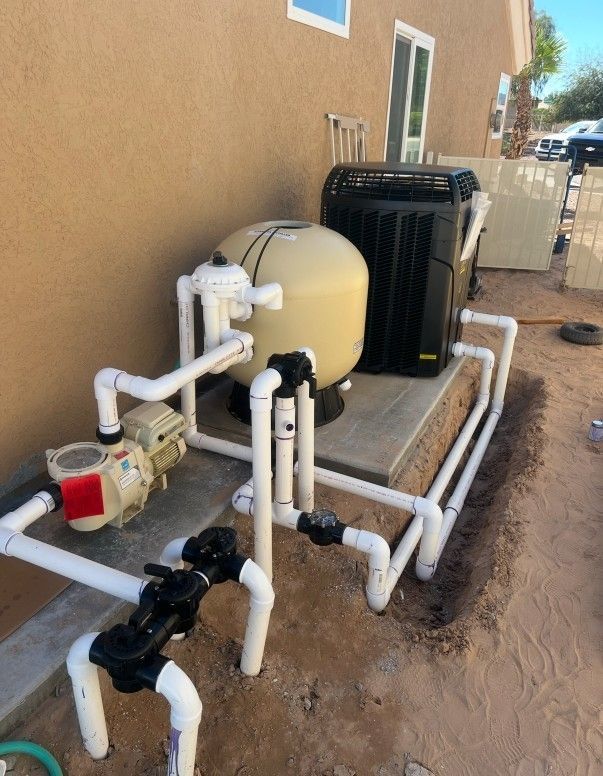 Pool equipment, including pump, filter, and heater, with white PVC piping, next to a beige wall.