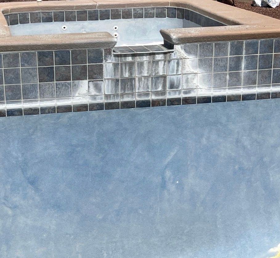 Empty swimming pool with dark tiles and a shallow jacuzzi area.