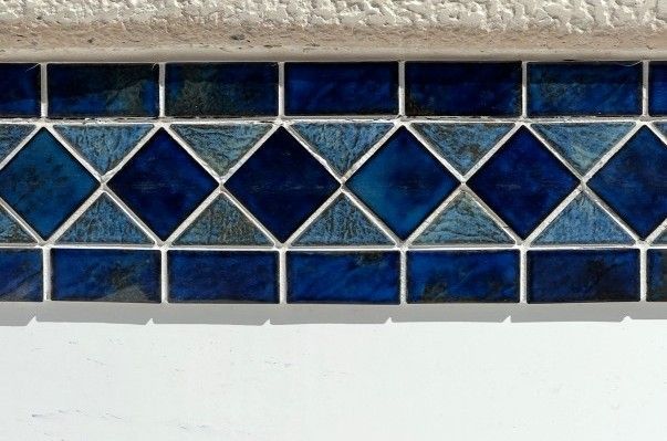 Blue diamond and rectangular mosaic tile border, with white trim above and below.