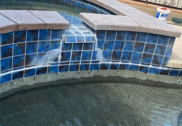 Blue tiled pool with steps; water partially visible. Stone coping.