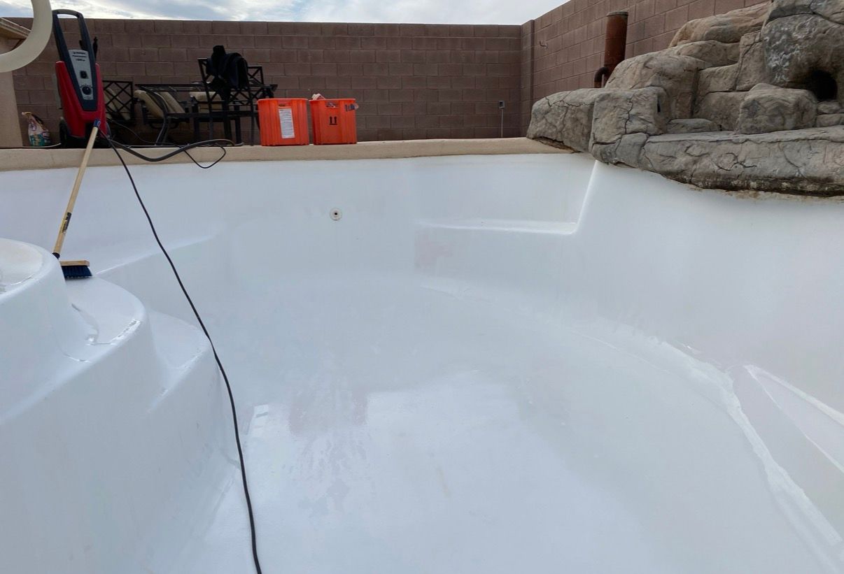 Newly painted white swimming pool with steps, a rock feature, and cleaning supplies.
