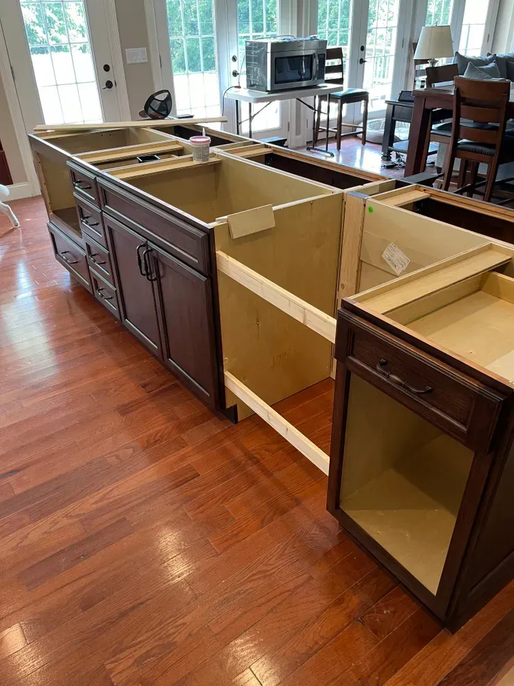 A kitchen cabinet is being built in a room with hardwood floors.