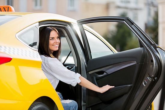 A woman is getting out of a taxi with her door open.
