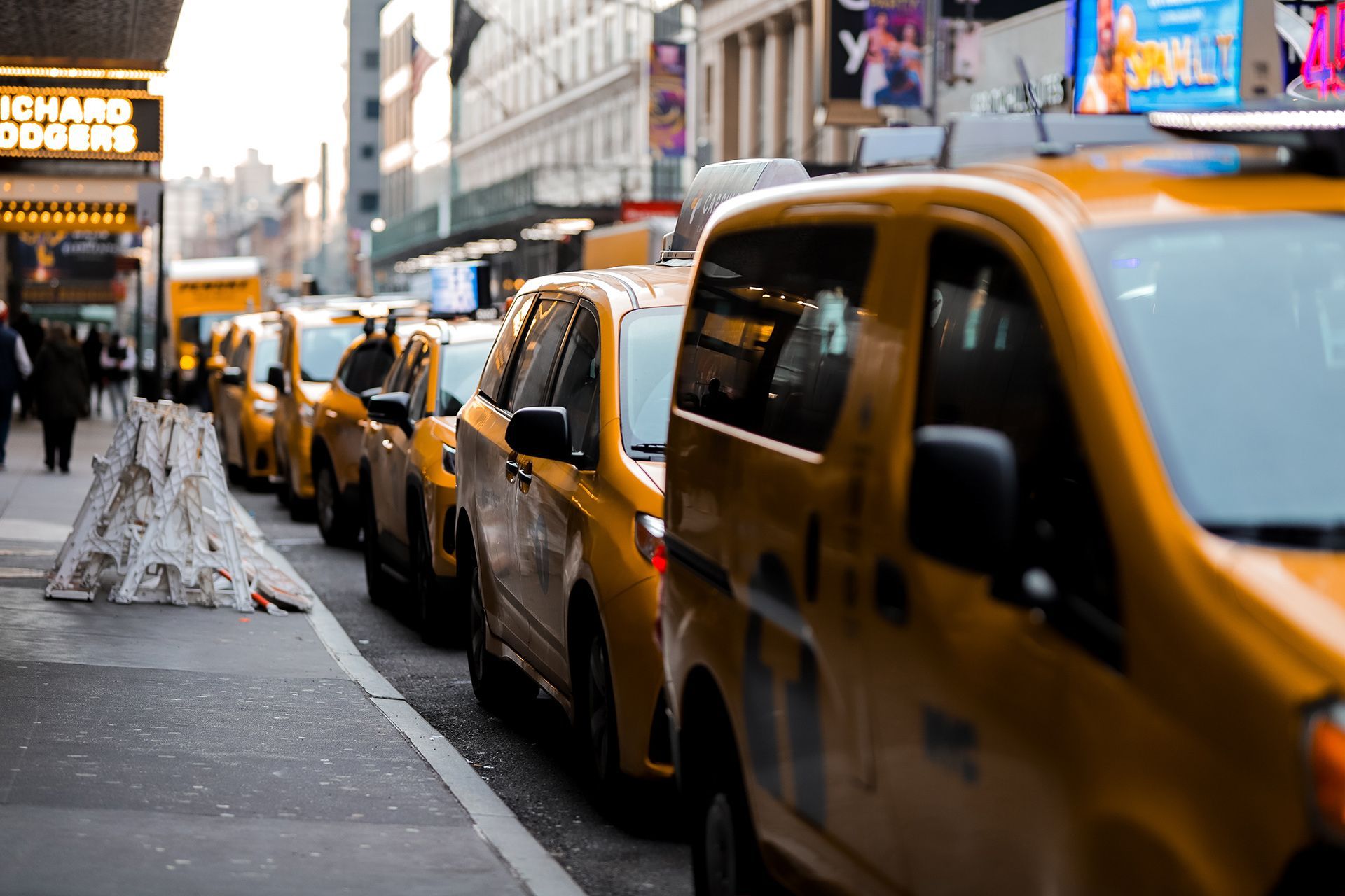 A row of yellow taxis are lined up on a city street.