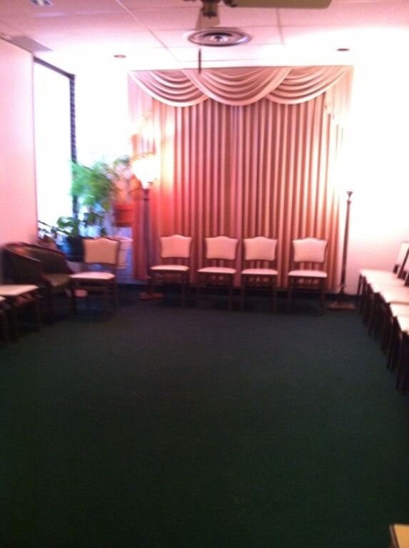 Empty room with chairs, green carpet, and a curtained backdrop.