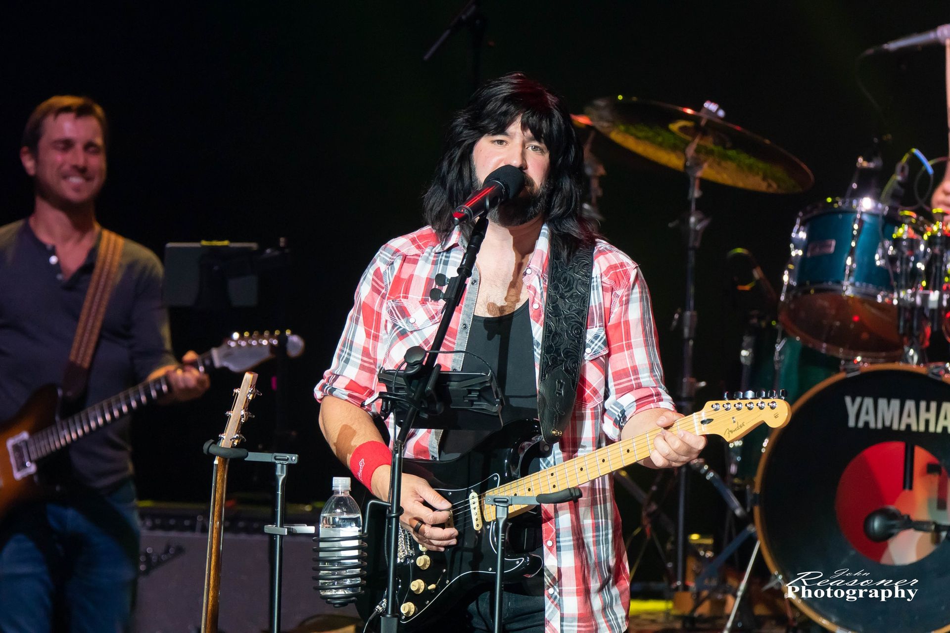 A man playing a guitar in front of a yamaha drum