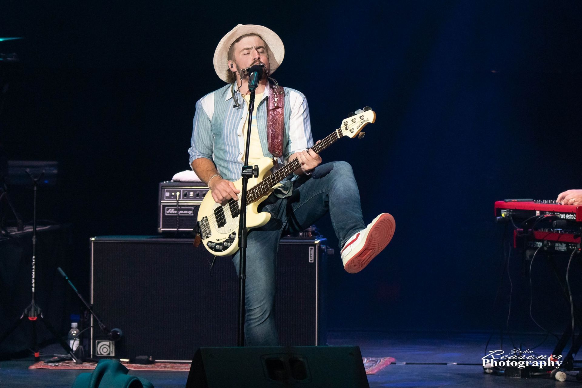 A man is playing a guitar and singing into a microphone on a stage.