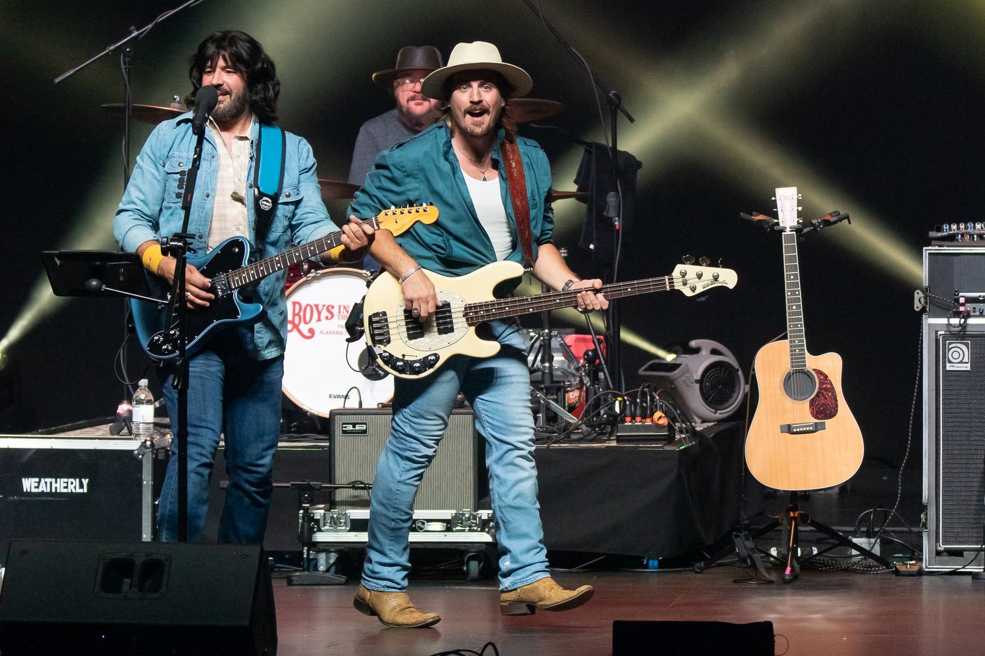 A man in a hat is playing a guitar on stage