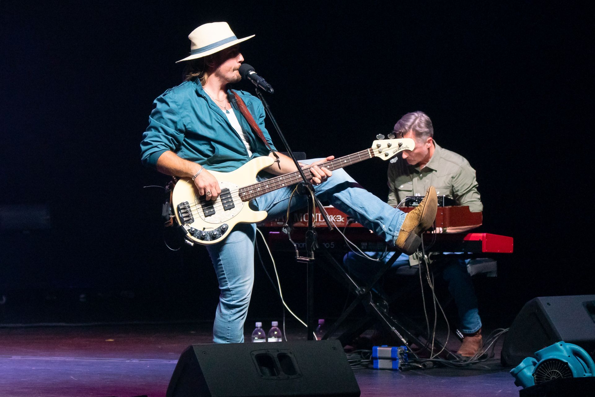 A man singing into a microphone while playing a guitar