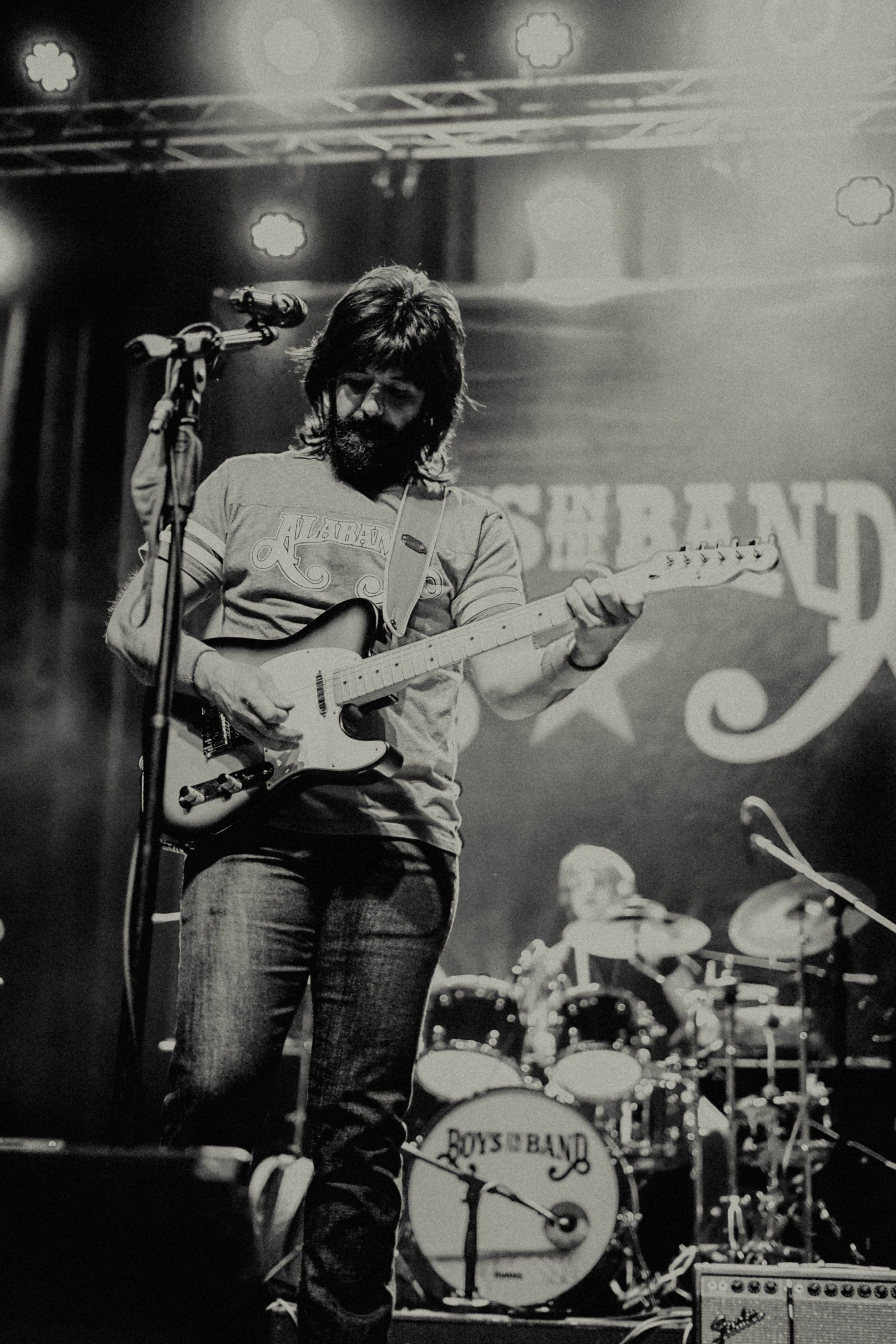 A black and white photo of a man playing a guitar and singing into a microphone