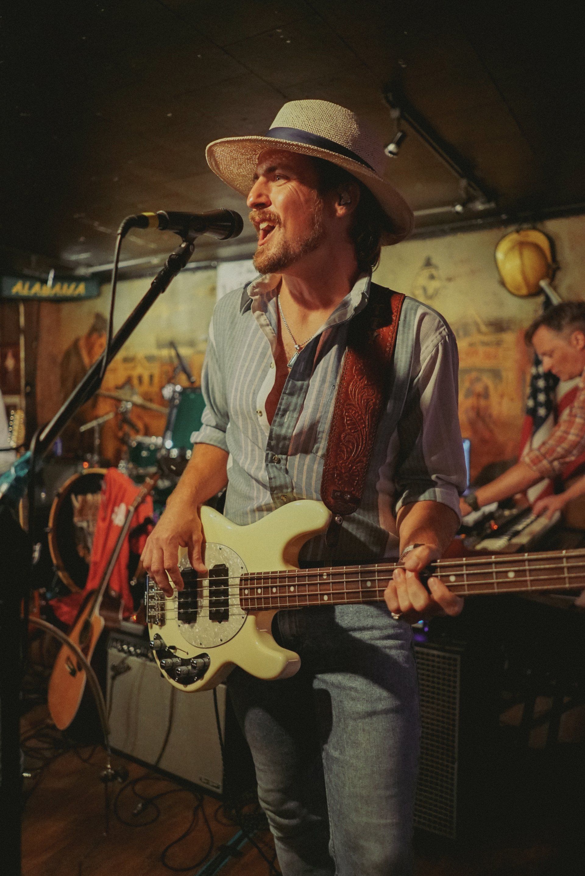 A man in a cowboy hat is playing a guitar and singing into a microphone