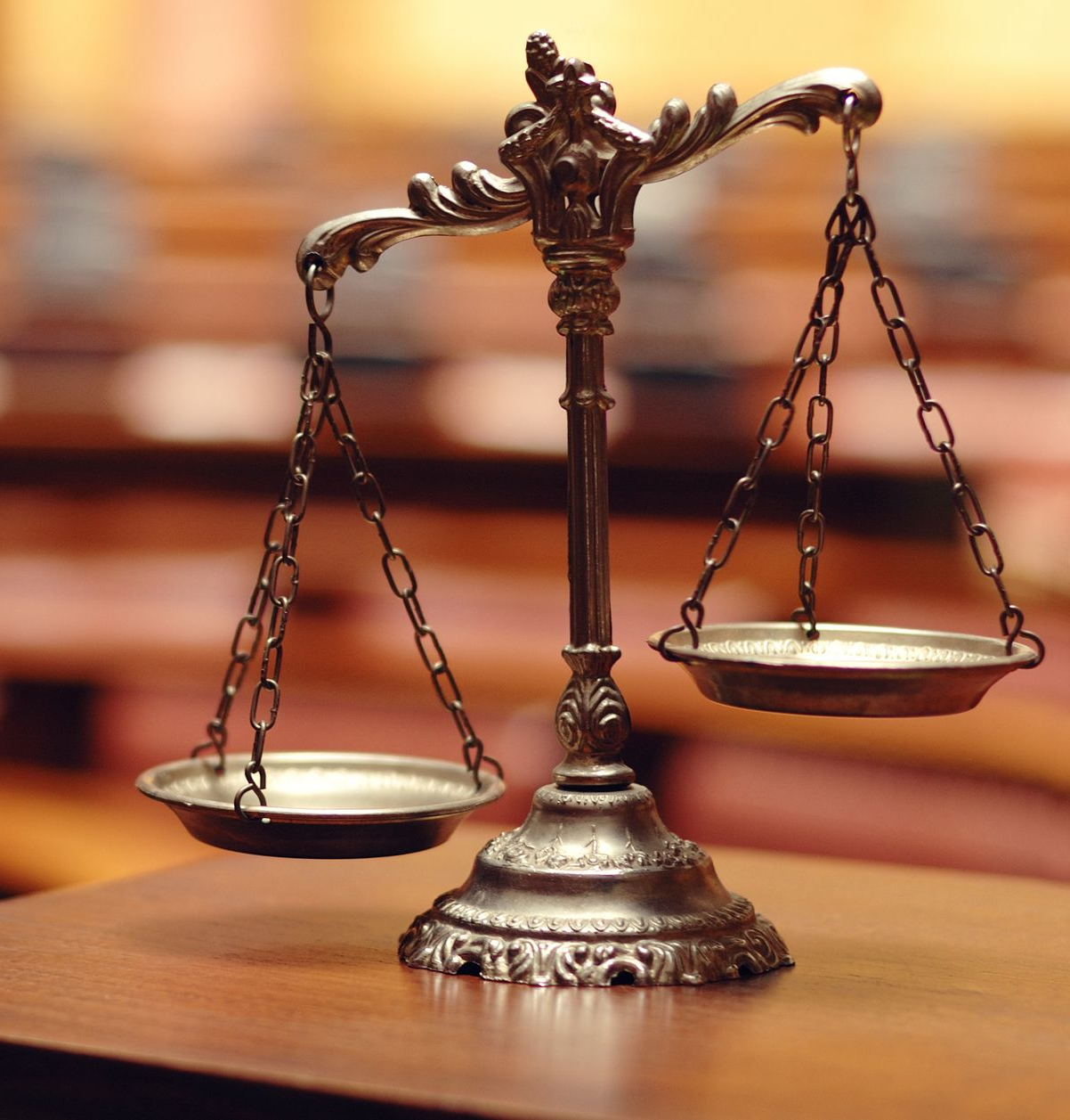 Antique balance scale on a wooden table, in a courtroom setting.