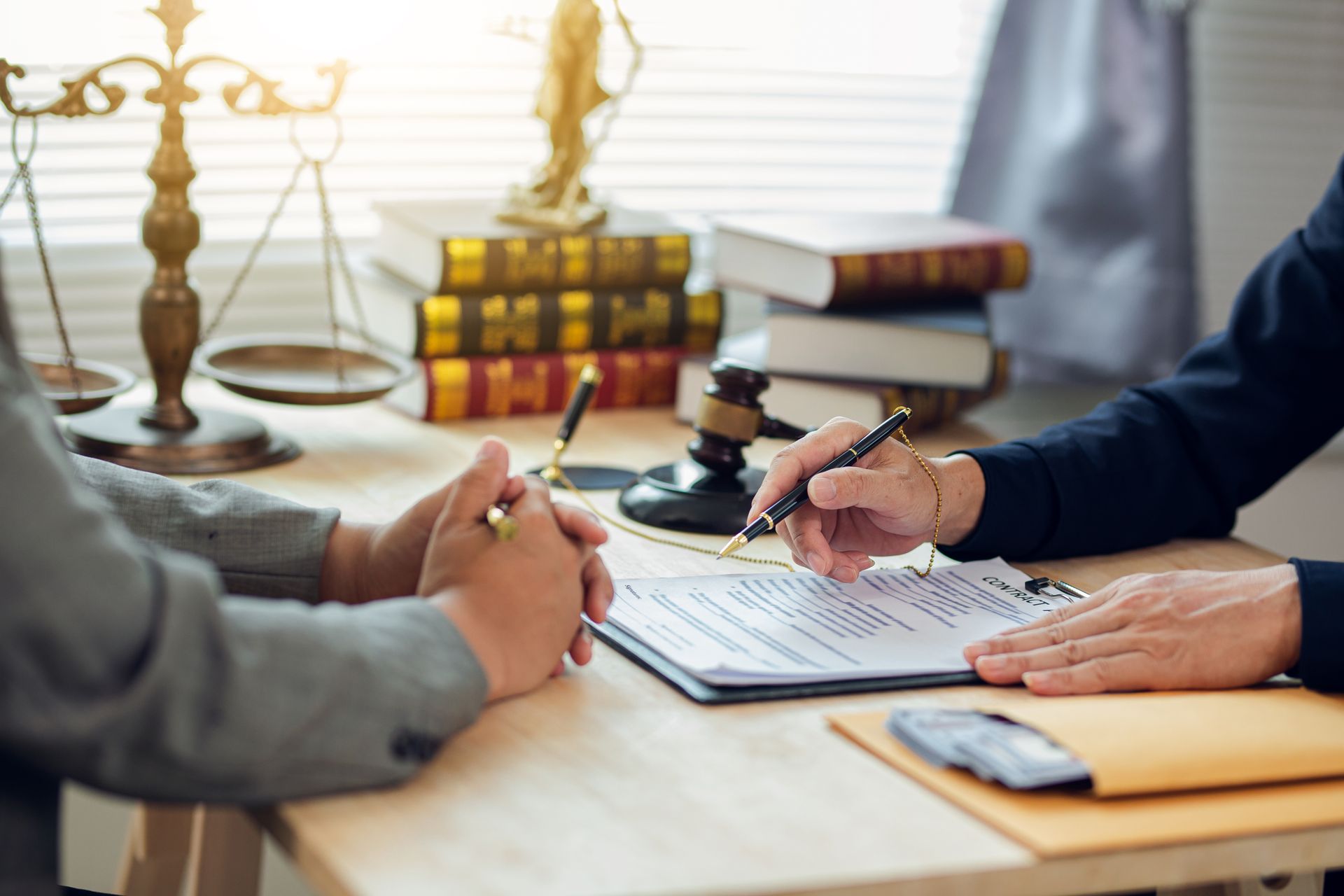 Person signing a document, legal setting with scales of justice and law books.