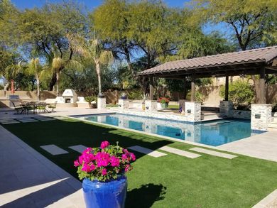 A large swimming pool with a blue pot of flowers in front of it.