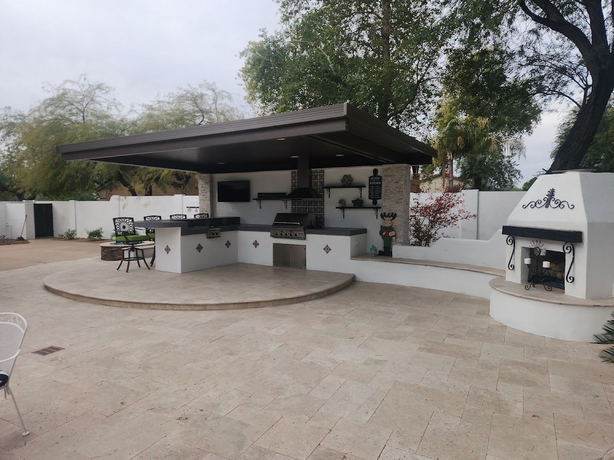 A large outdoor kitchen with a fireplace in the backyard