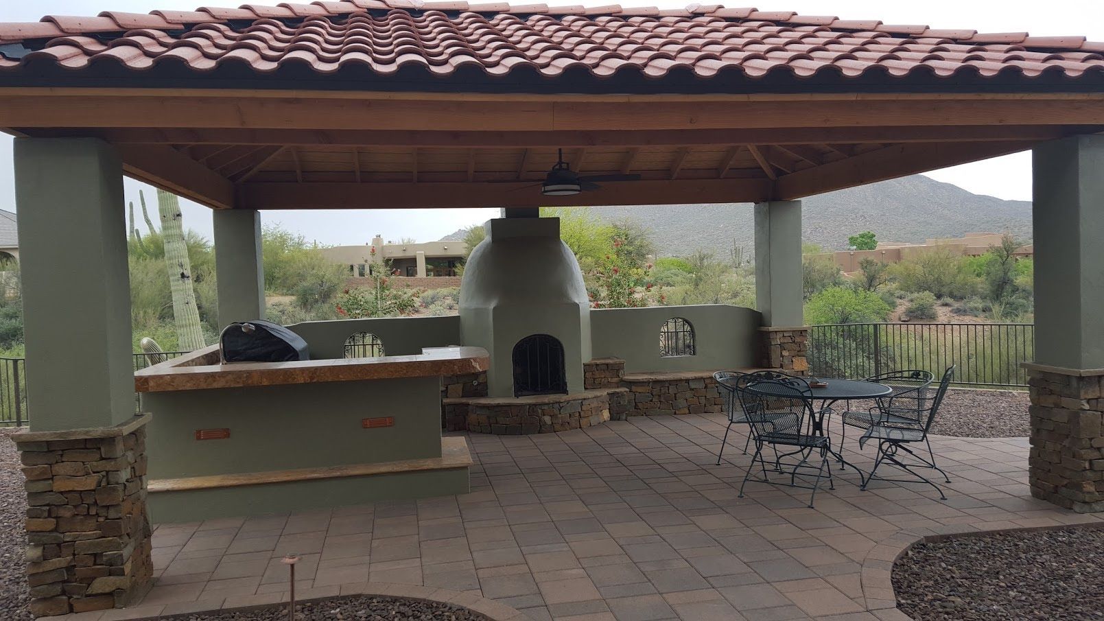 A gazebo with a fireplace and a table and chairs underneath it.