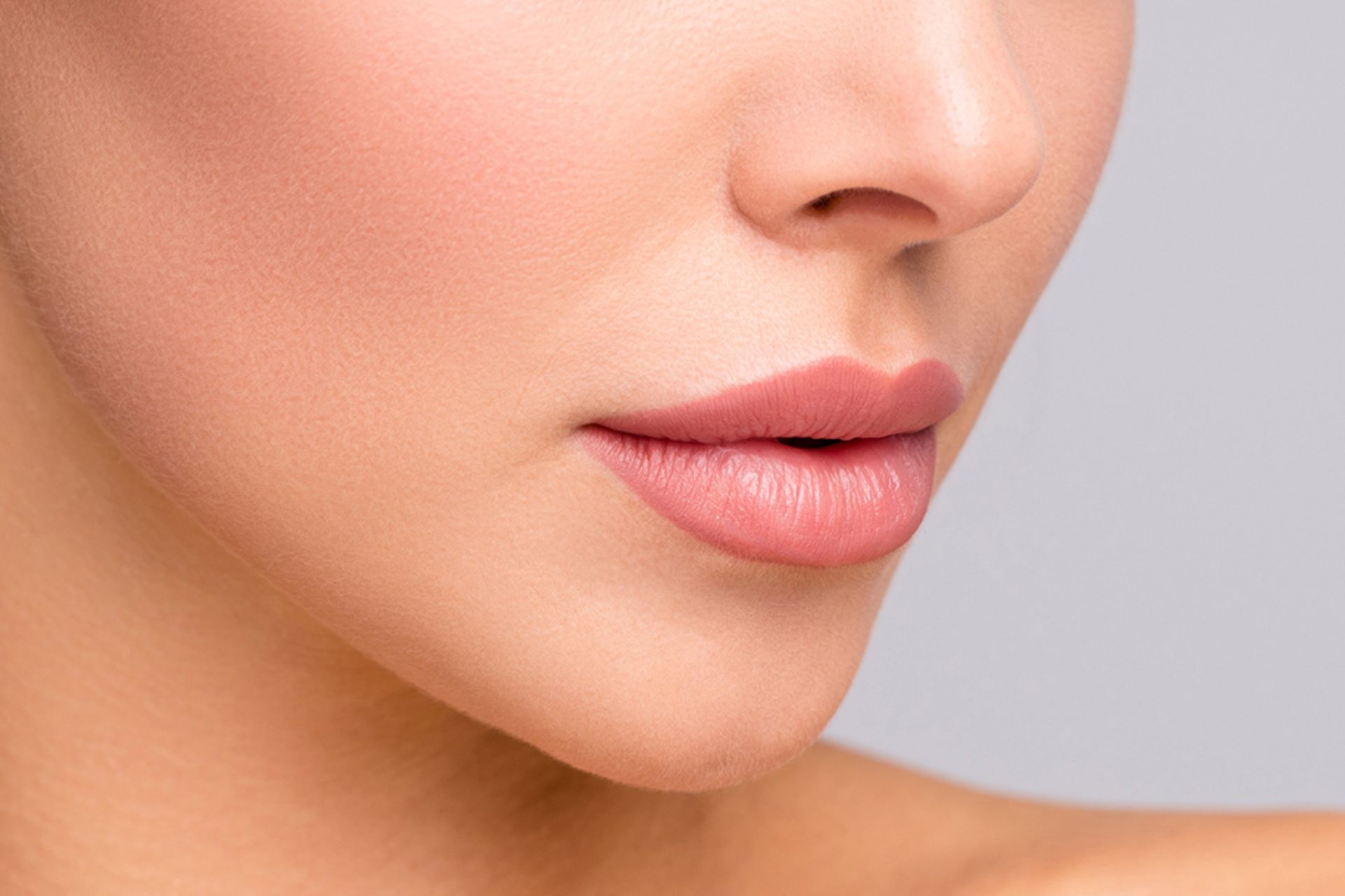 Close-up of a person's face showing smooth skin, a small nose, and full, pink lips.