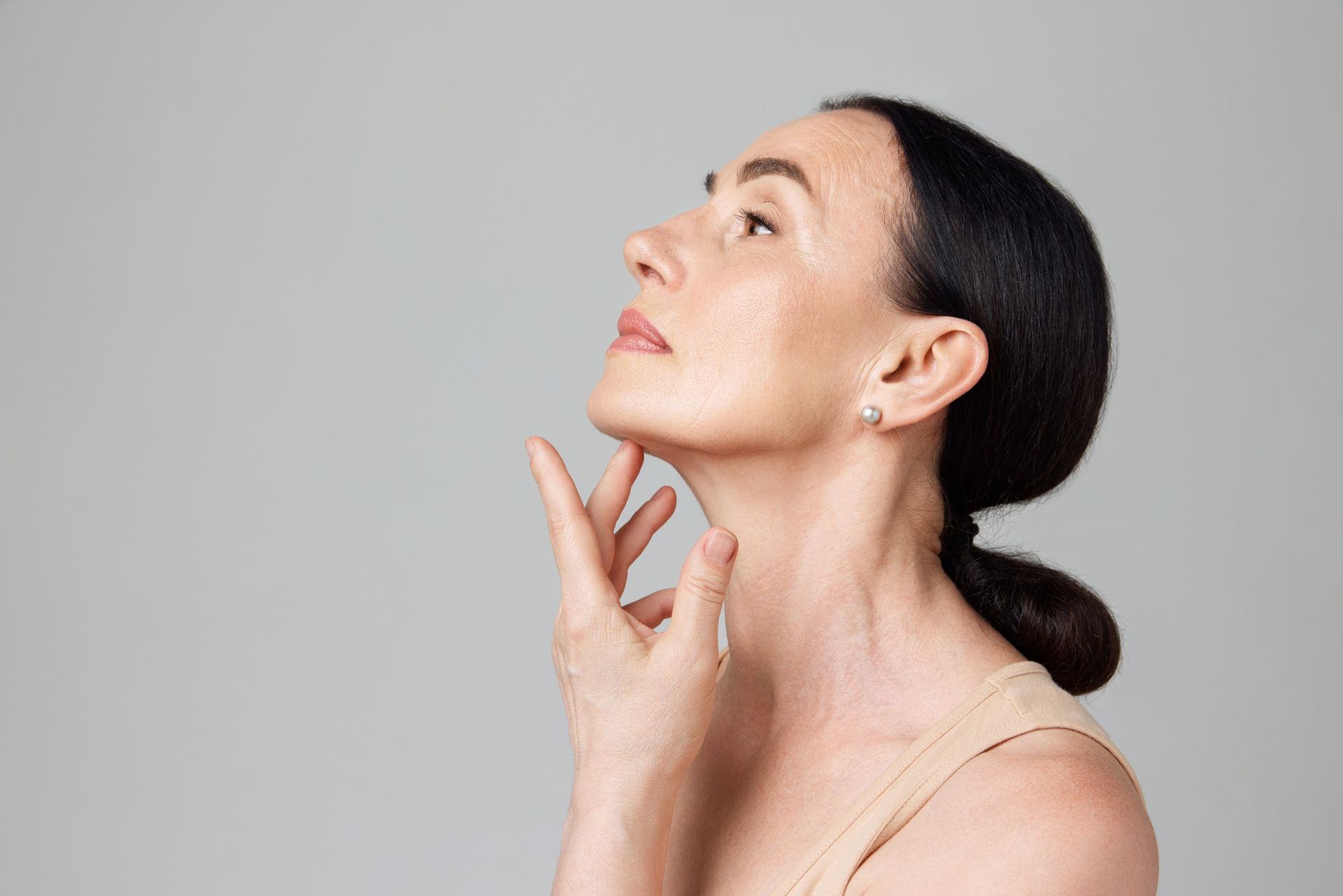 Woman looking up, hand on her neck.