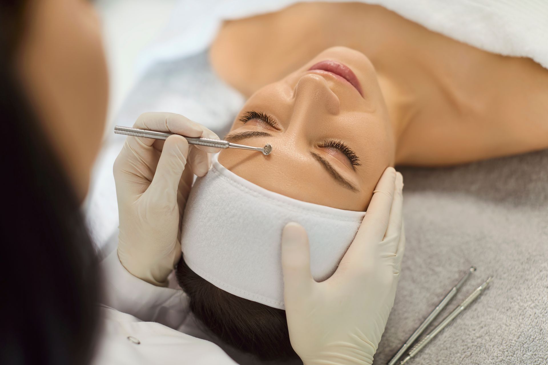 Cosmetic procedure on a woman’s face with gloved hands using a syringe near the chin
