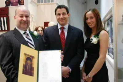 A man in a suit and tie is holding a certificate